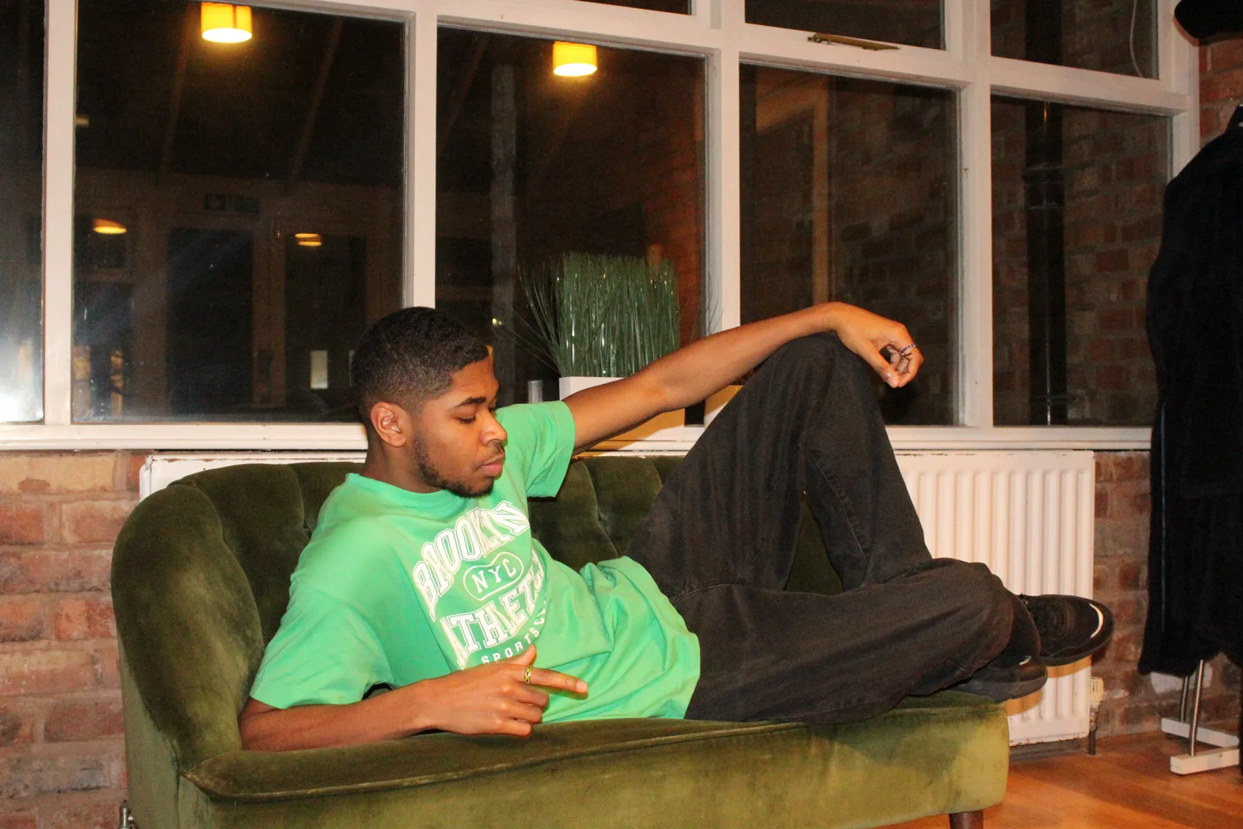 Jesse Ayo reclining on a green velvet sofa